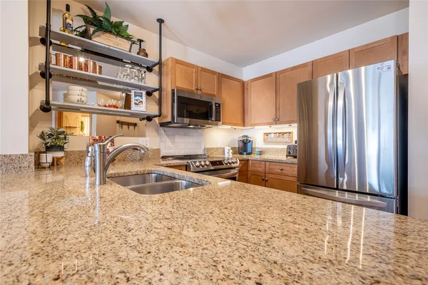 a kitchen with granite countertop a stove a sink and a microwave