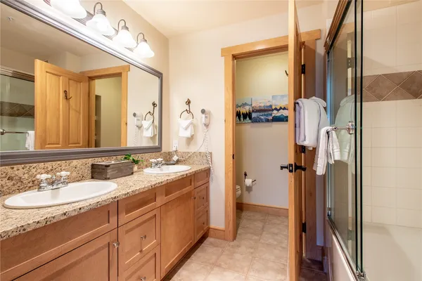 a bathroom with a granite countertop sink mirror and a shower