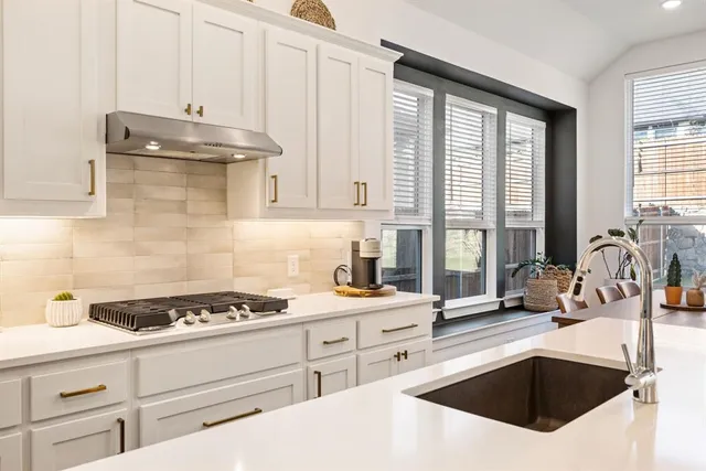 a kitchen with granite countertop a sink a stove and cabinets