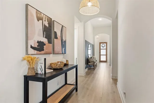 a hallway with painting on the wall and a wooden floor