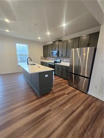 a kitchen with stainless steel appliances granite countertop a refrigerator a sink dishwasher a stove and a refrigerator