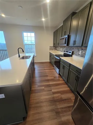 a large kitchen with stainless steel appliances granite countertop a sink a stove and a wooden floors