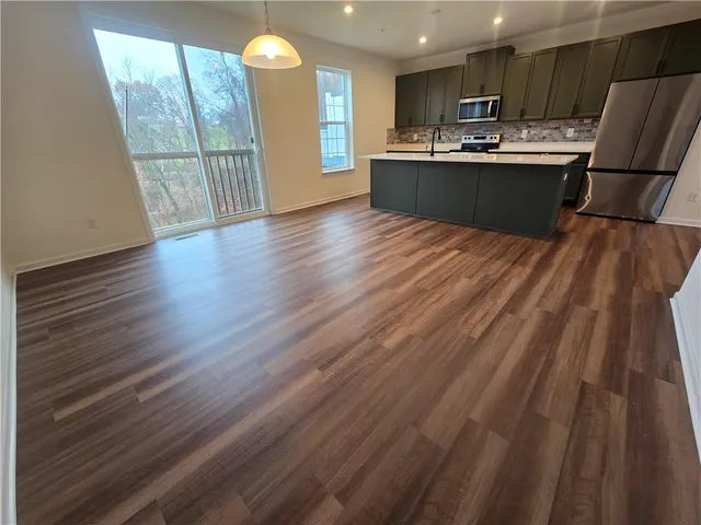 a kitchen with stainless steel appliances granite countertop a refrigerator a sink dishwasher a stove and white countertops with wooden floor