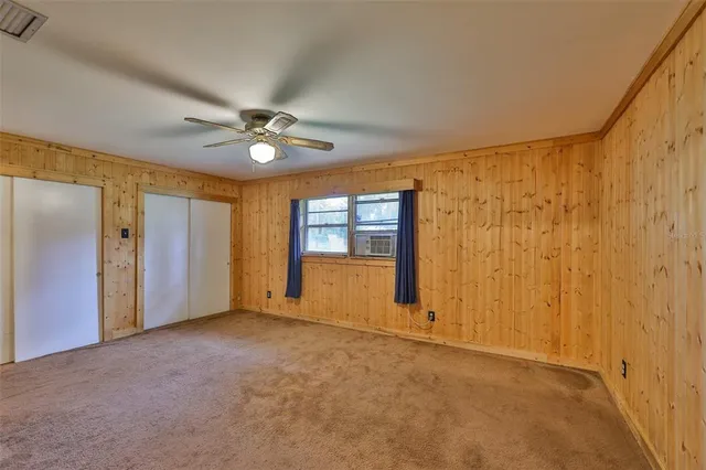 an empty room with closet and a ceiling fan
