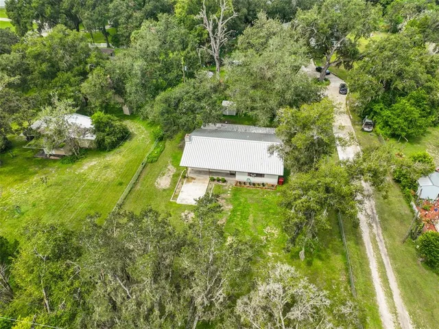 an aerial view of residential house with outdoor space and trees all around