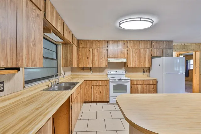 a kitchen with a sink a stove cabinets and wooden floor