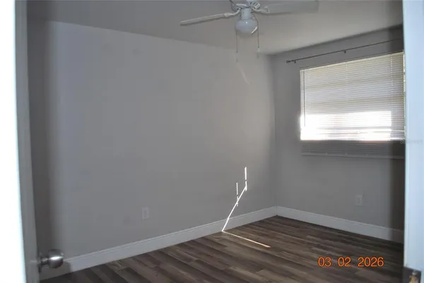 a view of an empty room with wooden floor and a window