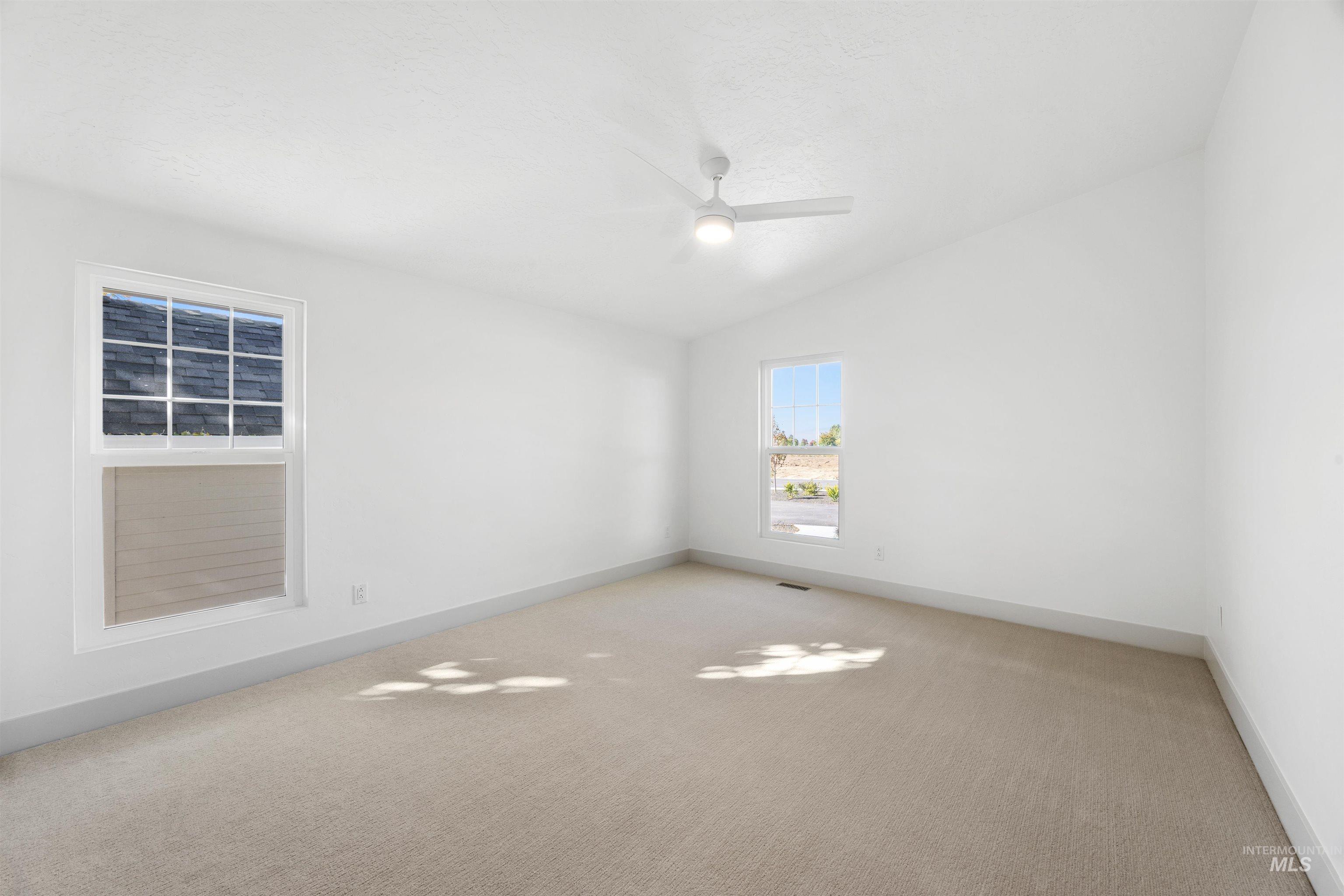 2141 West Beacon Light Road Eagle, ID 83616 - Photo 22 of 46 Carpeted spare room featuring vaulted ceiling and ceiling fan