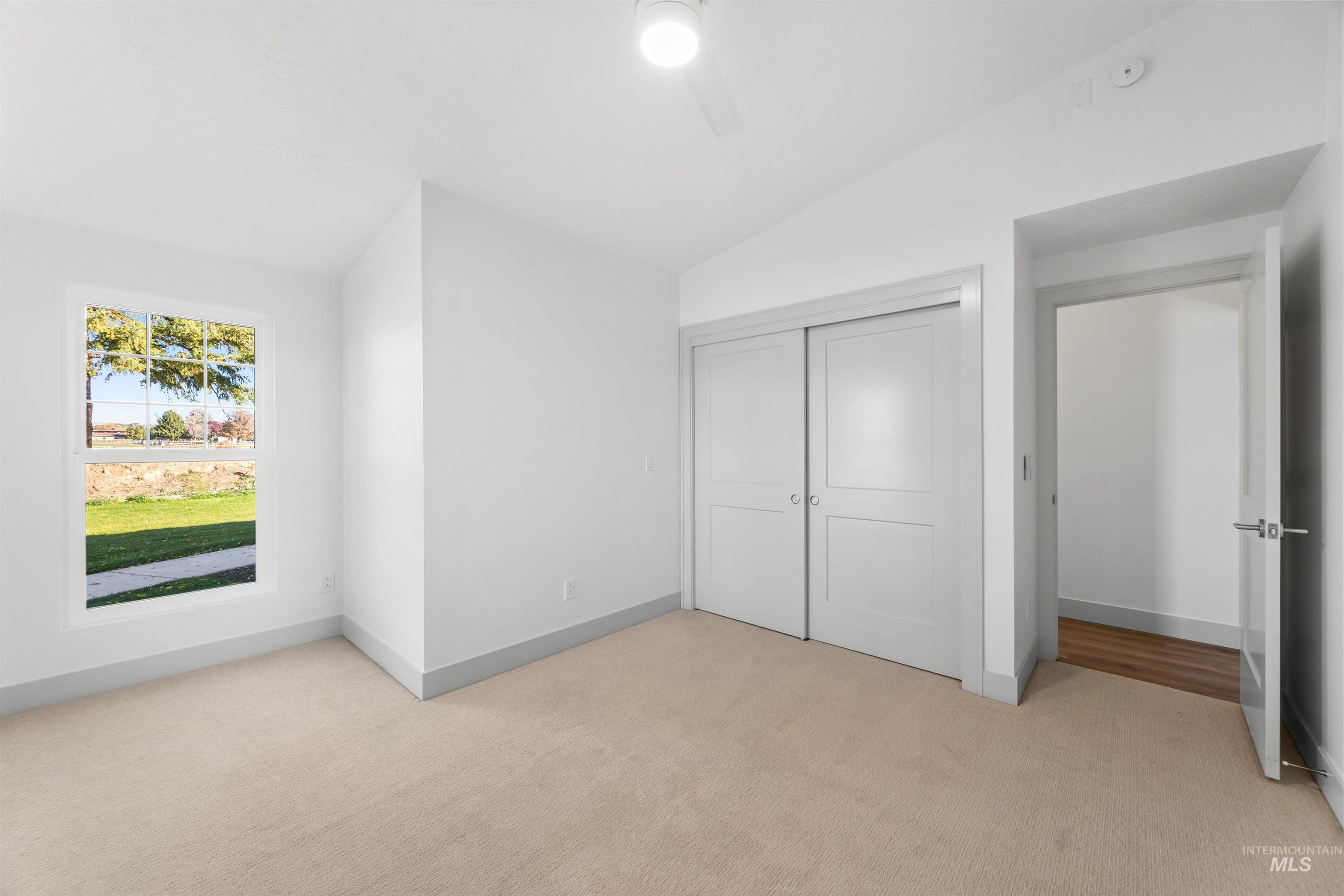 2141 West Beacon Light Road Eagle, ID 83616 - Photo 25 of 46 Unfurnished bedroom featuring vaulted ceiling, light carpet, a closet, and ceiling fan