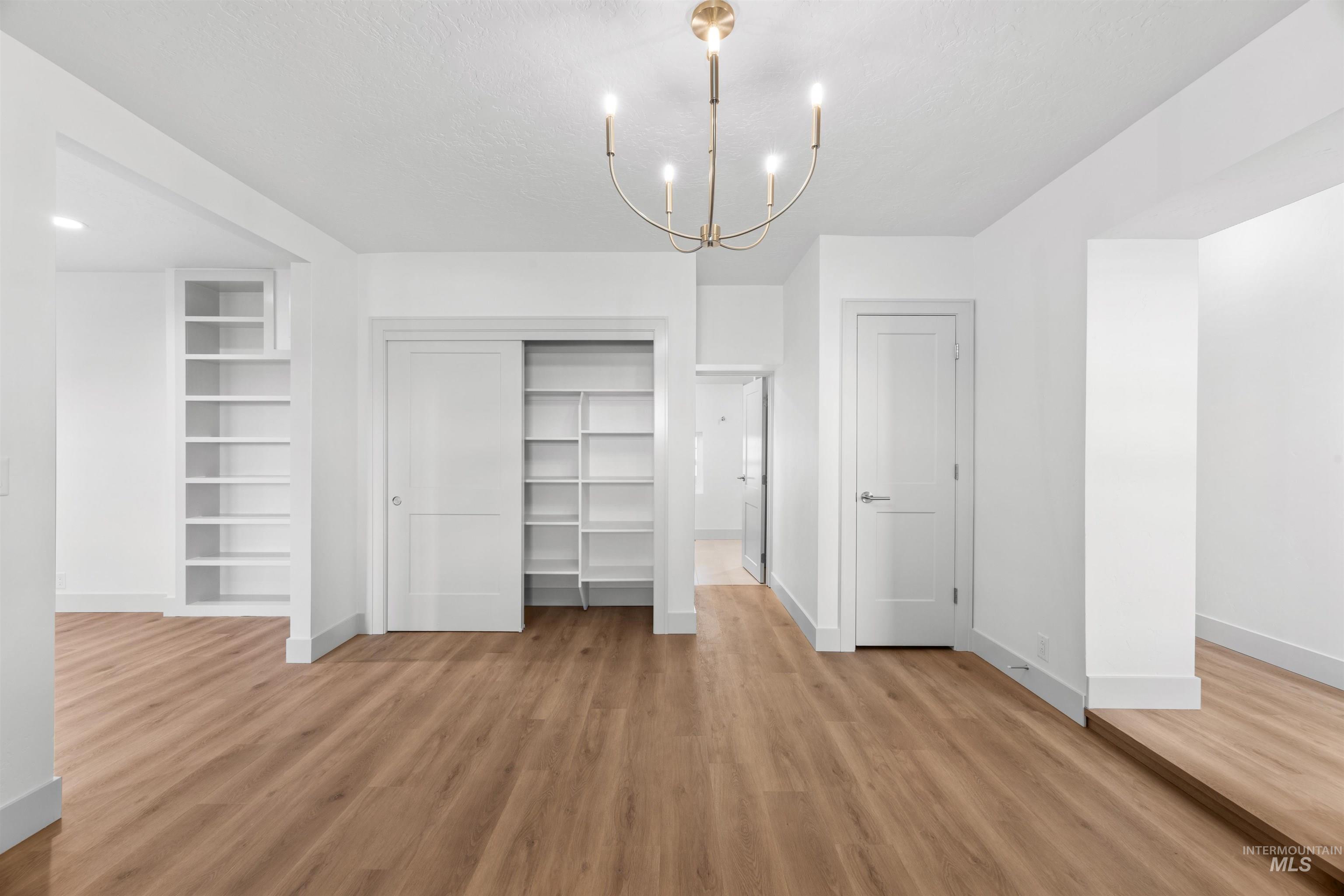 2141 West Beacon Light Road Eagle, ID 83616 - Photo 9 of 46 Unfurnished bedroom featuring a chandelier, light wood-style flooring, a closet, and a textured ceiling