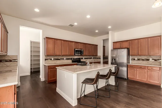 a kitchen with kitchen island granite countertop a sink cabinets and stainless steel appliances