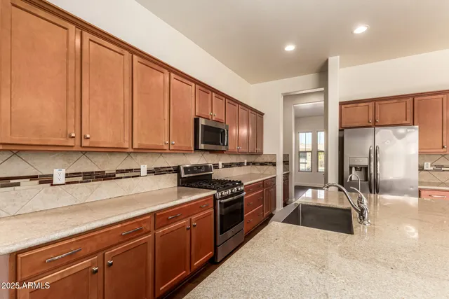 a kitchen with stainless steel appliances a stove top oven a refrigerator a stove top oven and a center island