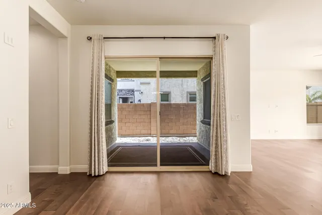 an empty room with wooden floor hallway and a chandelier