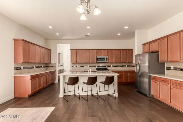 a kitchen with stainless steel appliances a stove a sink a refrigerator and white cabinets with wooden floor