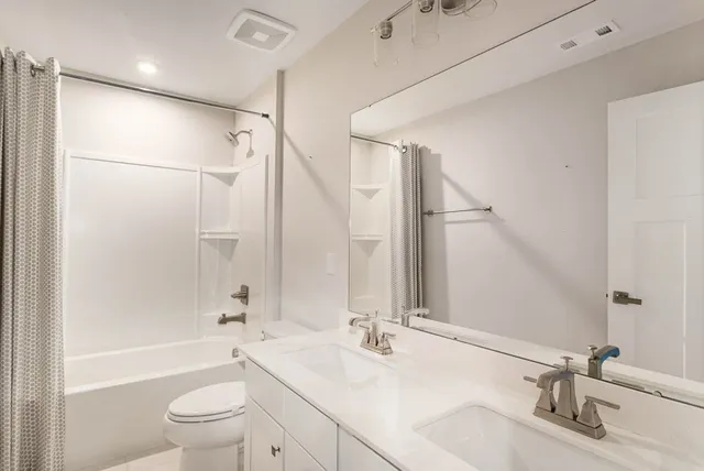 a bathroom with a bathtub shower sink vanity mirror and toilet