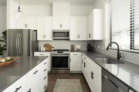 a kitchen with stainless steel appliances granite countertop a sink stove and refrigerator