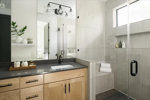 a bathroom with a granite countertop sink a mirror and shower