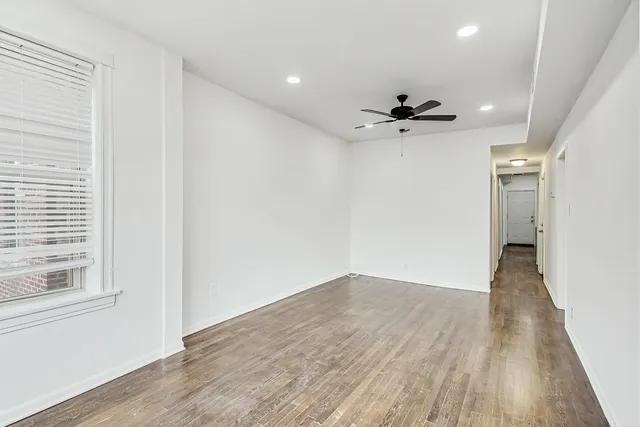 a view of a big room with wooden floor a ceiling fan and windows