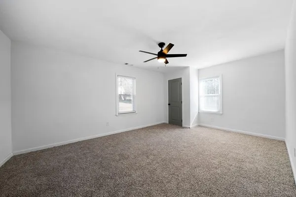 an empty room with windows and ceiling fan