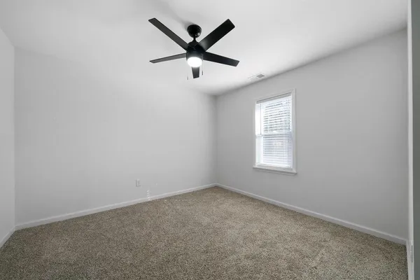 an empty room with a window and a fan