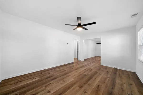 a view of empty room with wooden floor and ceiling fan