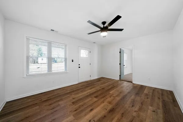 a view of empty room with wooden floor and window