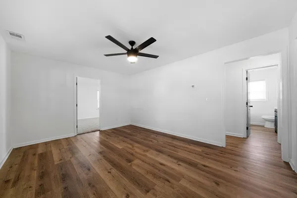 an empty room with wooden floor and a ceiling fan