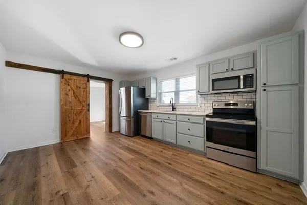 a kitchen with granite countertop a refrigerator and a stove top oven