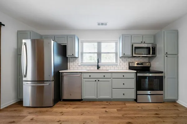 a kitchen with granite countertop a refrigerator stove and wooden floor