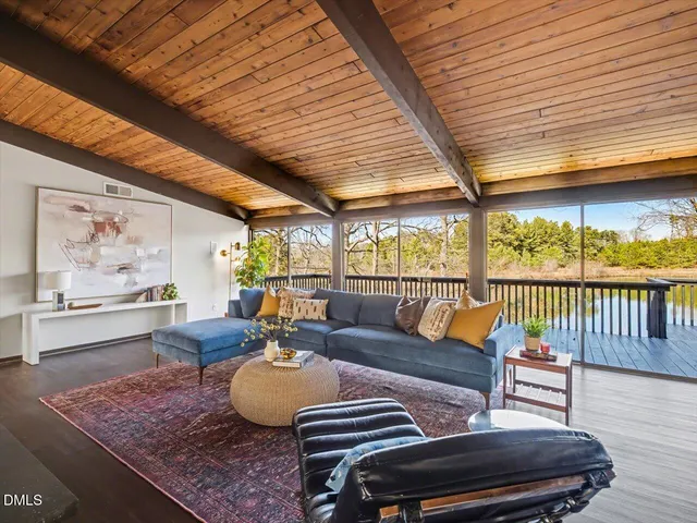 a view of wooden deck and lake with trees in the background