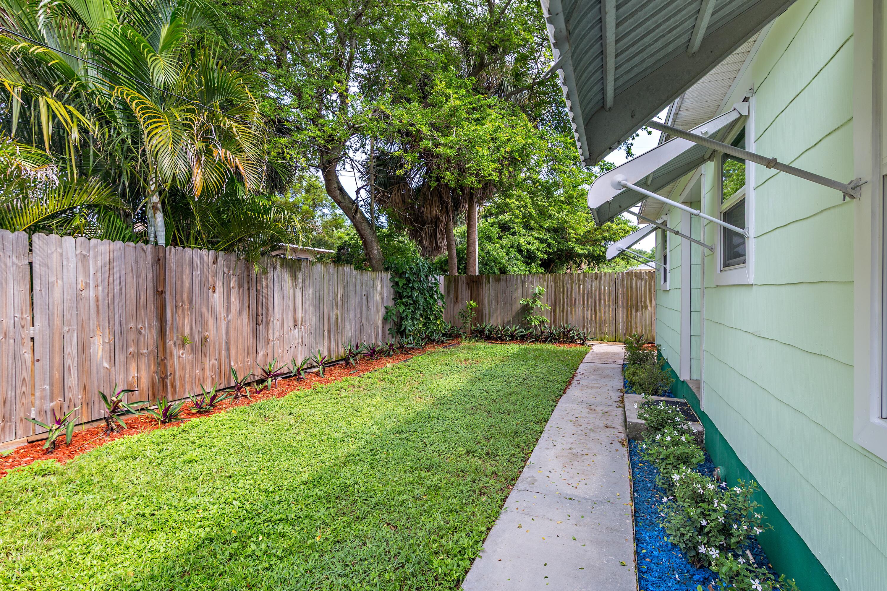 429 49th Street, Unit 2 West Palm Beach, FL 33407 - Photo 10 of 10 a view of a backyard with potted plants and a large tree