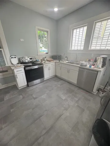 a large white kitchen with granite countertop a sink cabinets and window