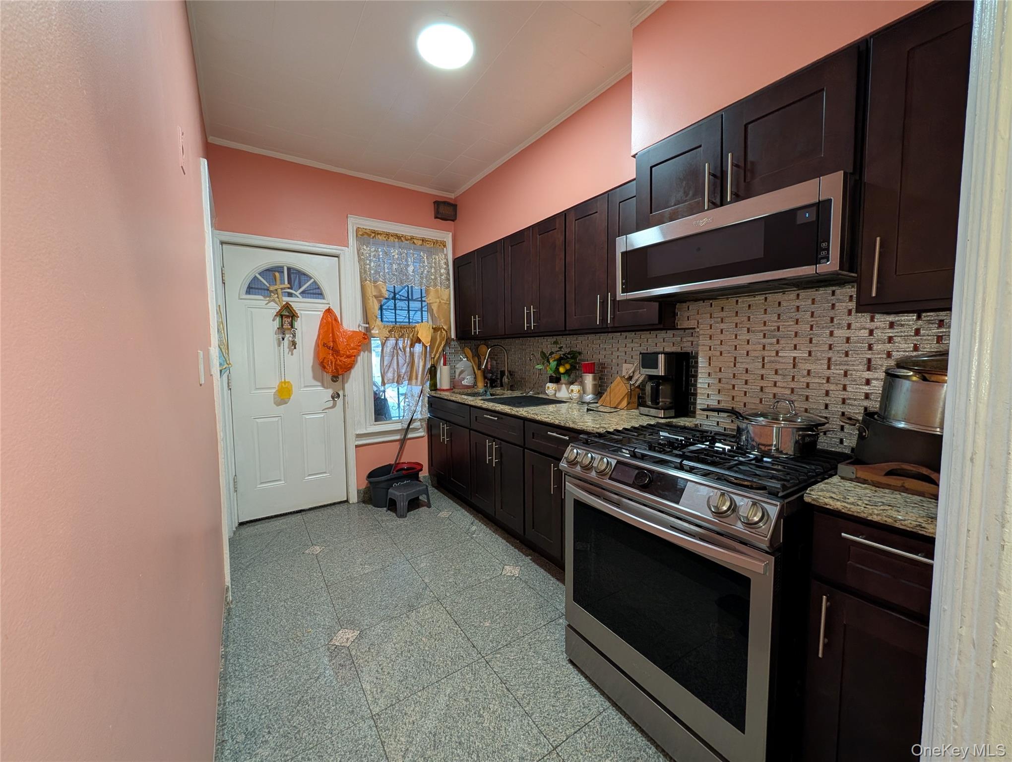 90-46 76th Street Queens, NY 11421 - Photo 14 of 32 a kitchen with stainless steel appliances a stove a microwave and cabinets