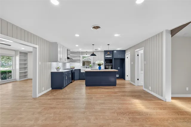 a kitchen with stainless steel appliances granite countertop a sink a stove and a wooden floors