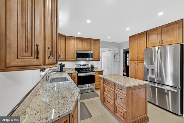 a kitchen with stainless steel appliances granite countertop a refrigerator a stove top oven a sink and dishwasher