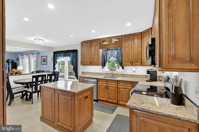 a kitchen with granite countertop kitchen island stainless steel appliances a sink stove and cabinets