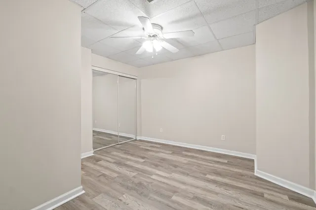 an empty room with a ceiling fan and wooden floor