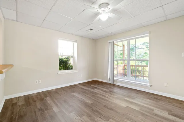 an empty room with wooden floor fan and windows