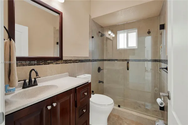 a bathroom with a sink a toilet a mirror and shower