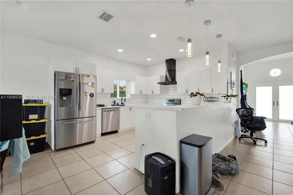 a kitchen with refrigerator and chairs
