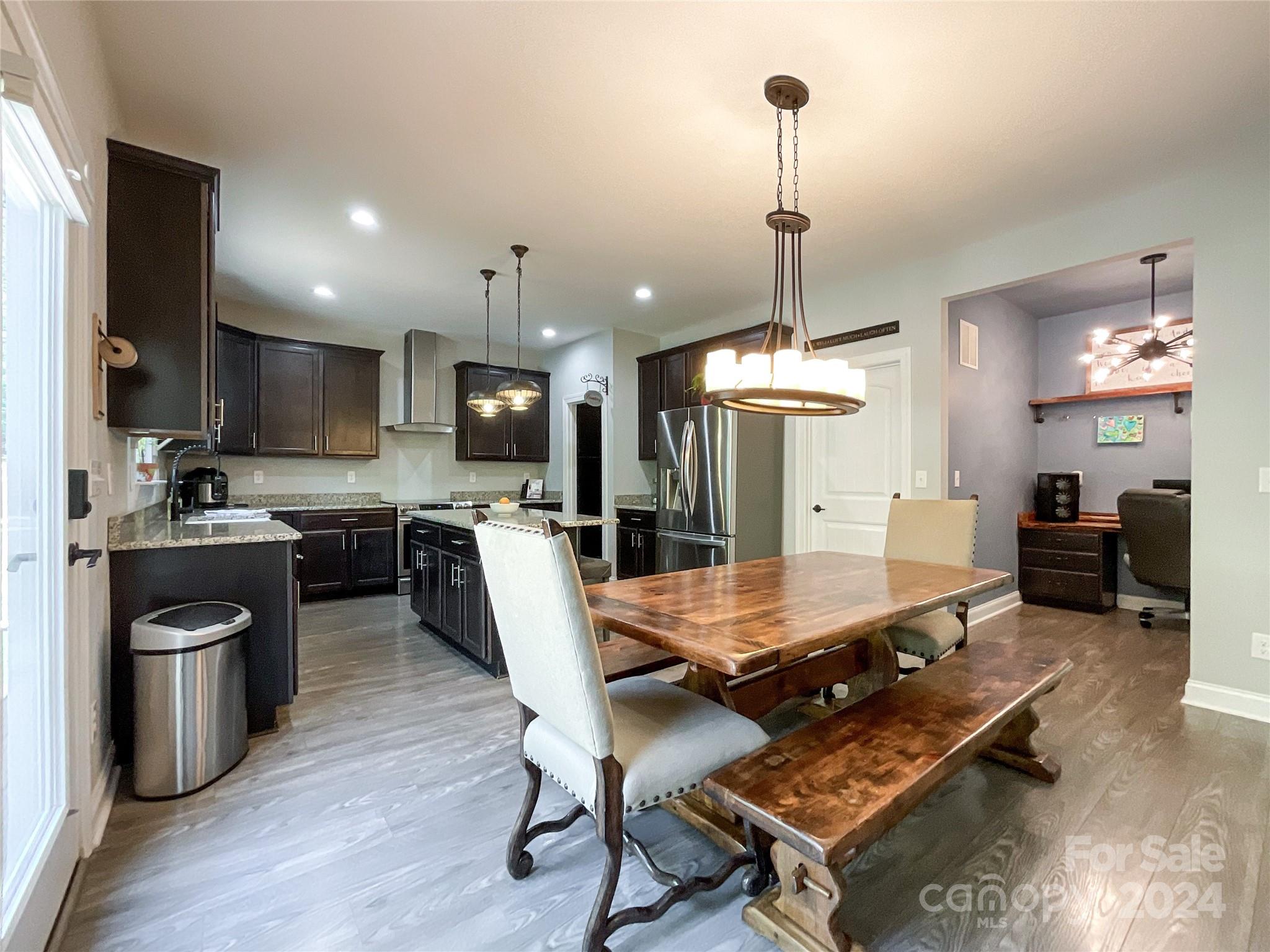 9408 Deer Run Road Waxhaw, NC 28173 - Photo 12 of 47 a room with stainless steel appliances kitchen island granite countertop a stove a refrigerator a kitchen island a dining table and chairs with wooden floor