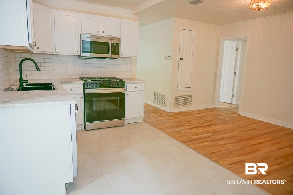 4667 Cottonwood Drive Mobile, AL 36608 - Photo 8 of 21 Kitchen featuring range, tasteful backsplash, white cabinetry, and sink