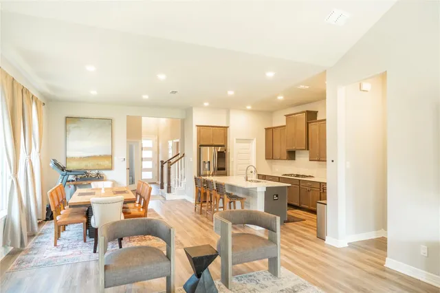 a large living room with stainless steel appliances kitchen island granite countertop a dining table chairs and a sink