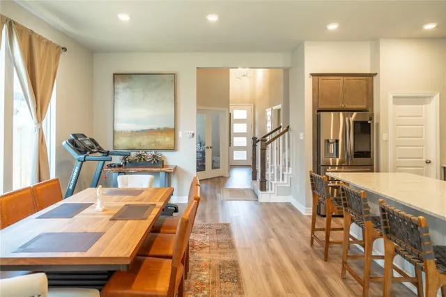 a dining hall with stainless steel appliances kitchen island granite countertop a refrigerator and wooden floor