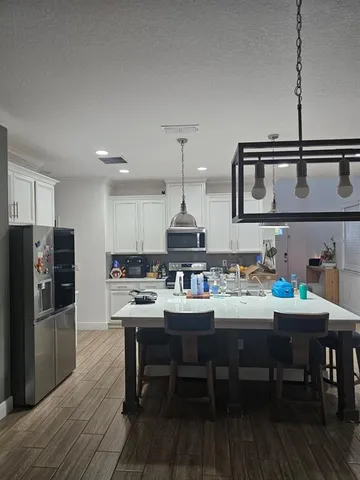 a kitchen with a dining table chairs and refrigerator