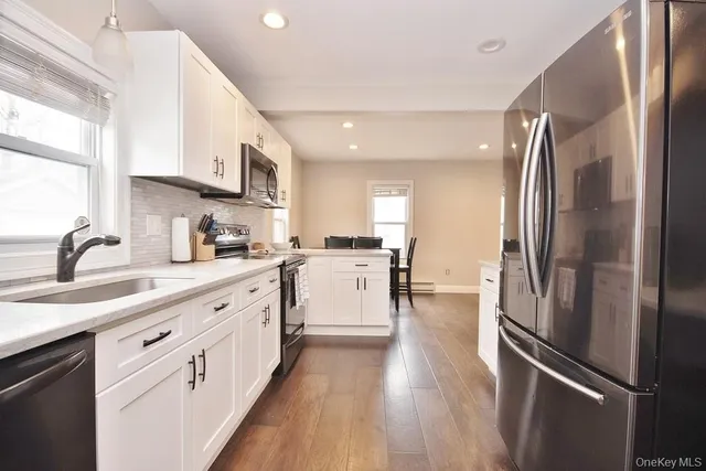 a kitchen with stainless steel appliances a refrigerator sink and white cabinets