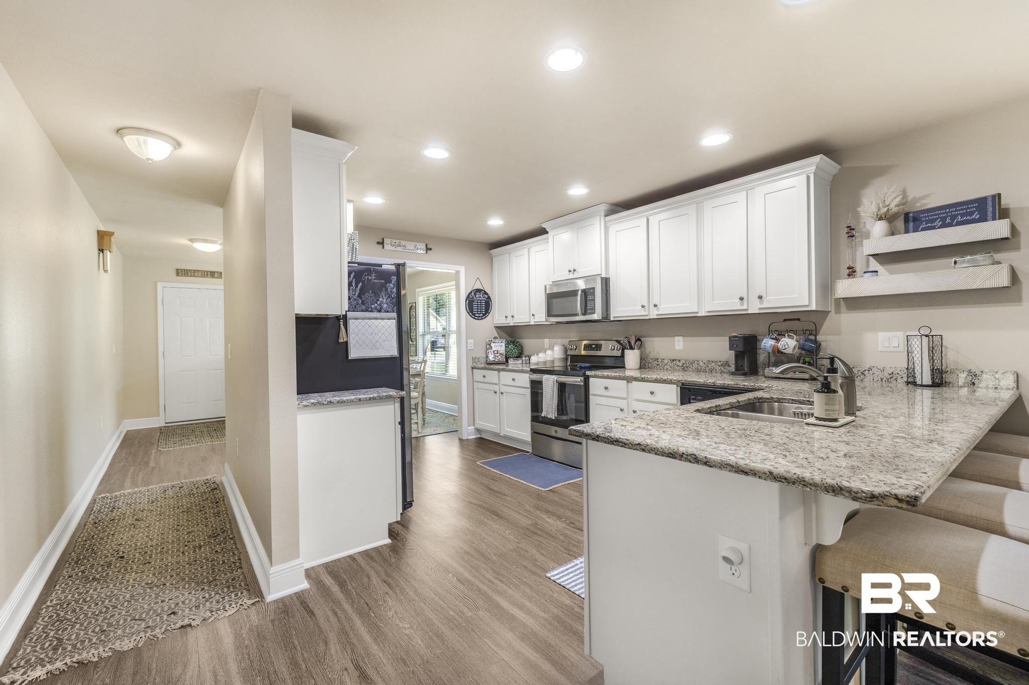 22043 Garland Loop Silverhill, AL 36576 - Photo 10 of 41 Kitchen featuring a peninsula, white cabinetry, stainless steel appliances, a breakfast bar area, and light stone counters