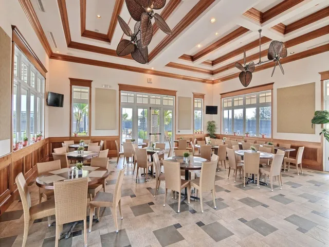 a room with lots of tables a large window and chairs