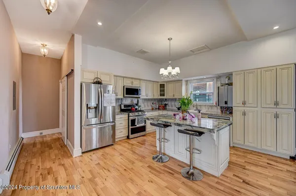 a living room with stainless steel appliances furniture a rug and a view of kitchen