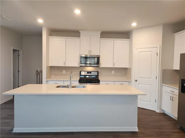 a kitchen with kitchen island a sink a stove a refrigerator and white cabinets
